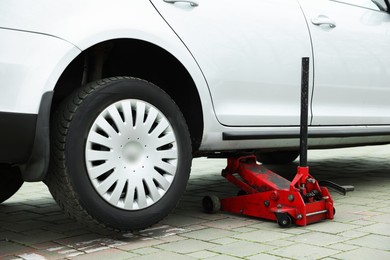 Photo of Car lifted by scissor jack on roadside outdoors