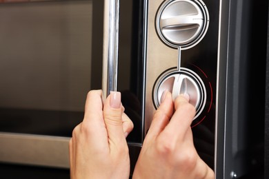 Photo of Woman turning on microwave at home, closeup