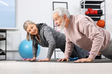 Smiling elderly couple exercising at home. Healthy leisure