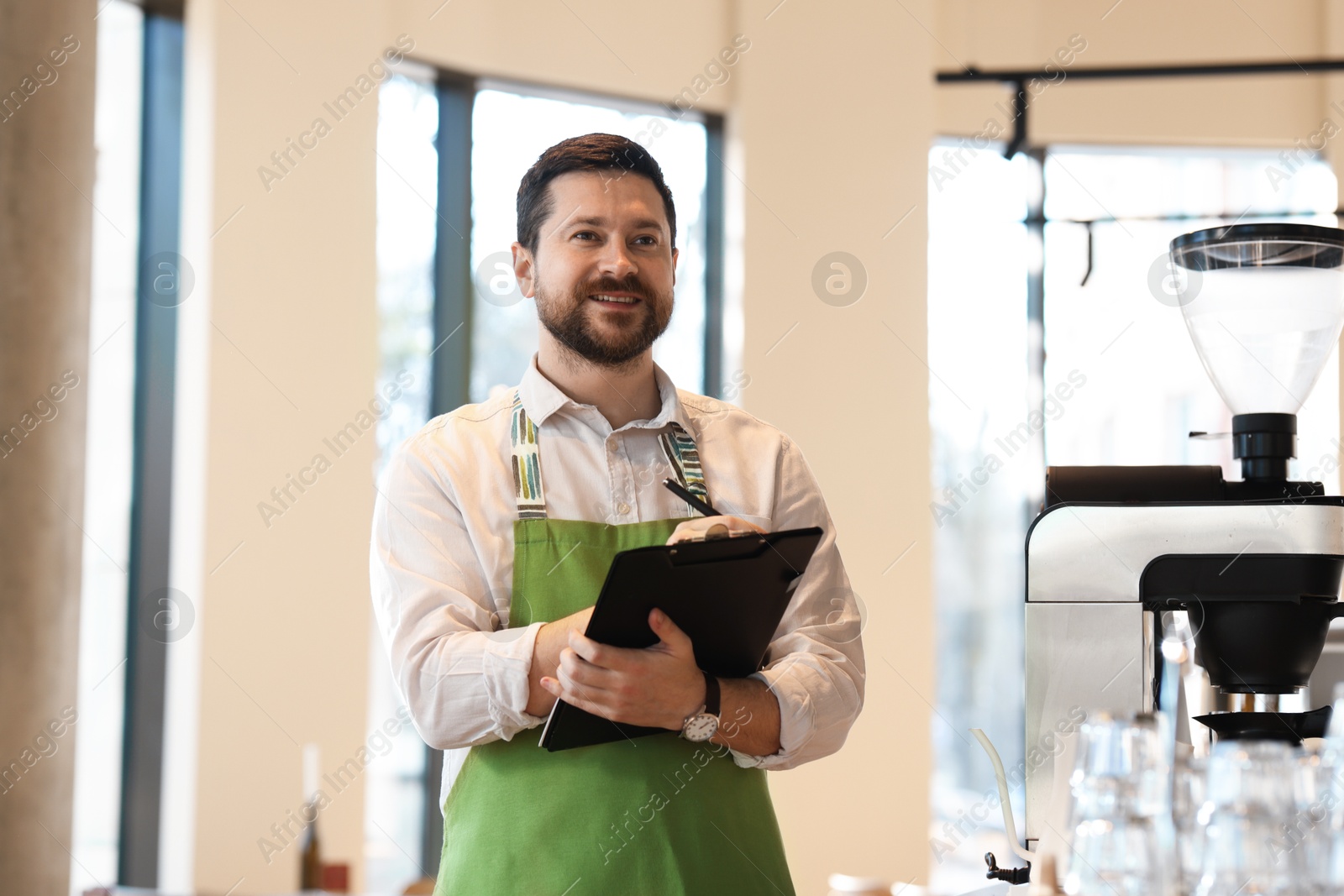 Photo of Smiling business owner working with clipboard in his cafe