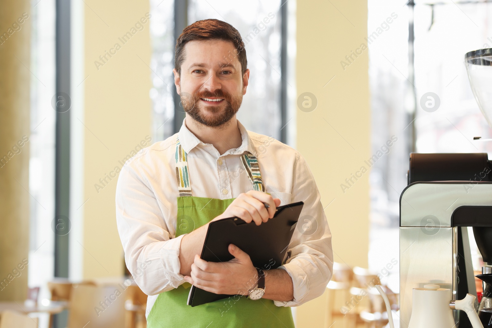 Photo of Portrait of smiling business owner with clipboard in his cafe