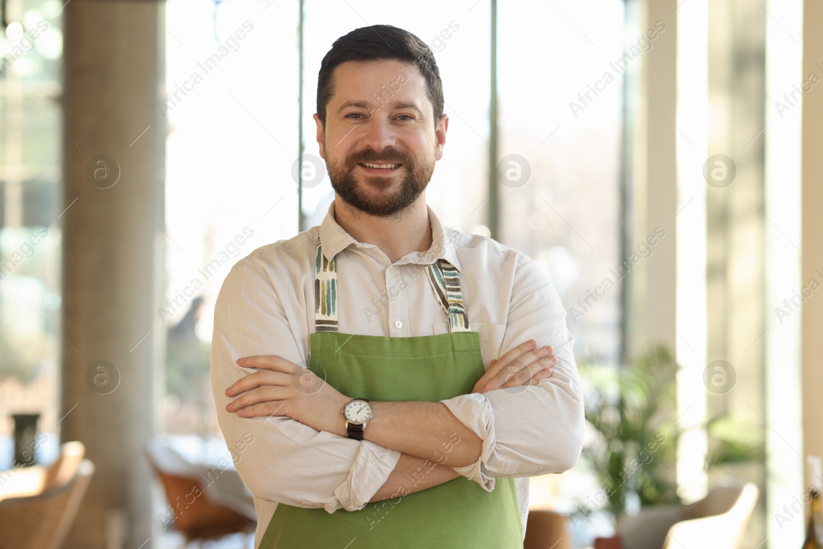 Photo of Portrait of smiling business owner with crossed arms in his cafe