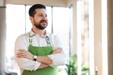 Smiling business owner with crossed arms in his cafe. Space for text