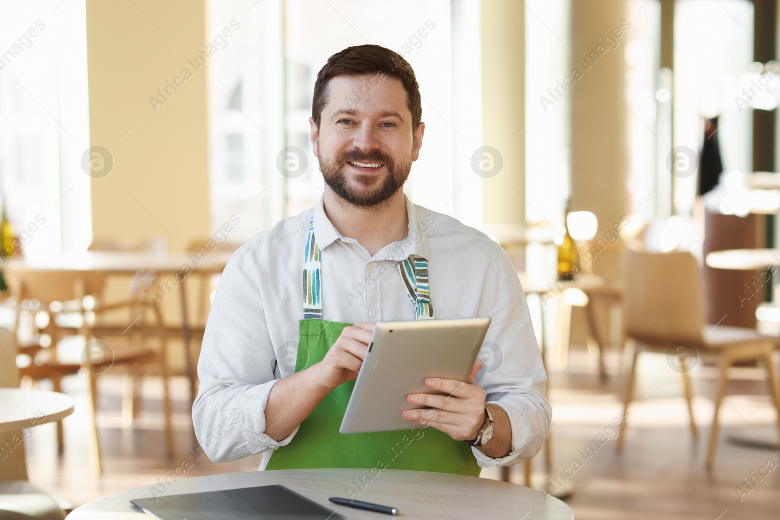 Photo of Smiling business owner with tablet in his cafe