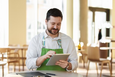 Handsome business owner working with tablet in his cafe