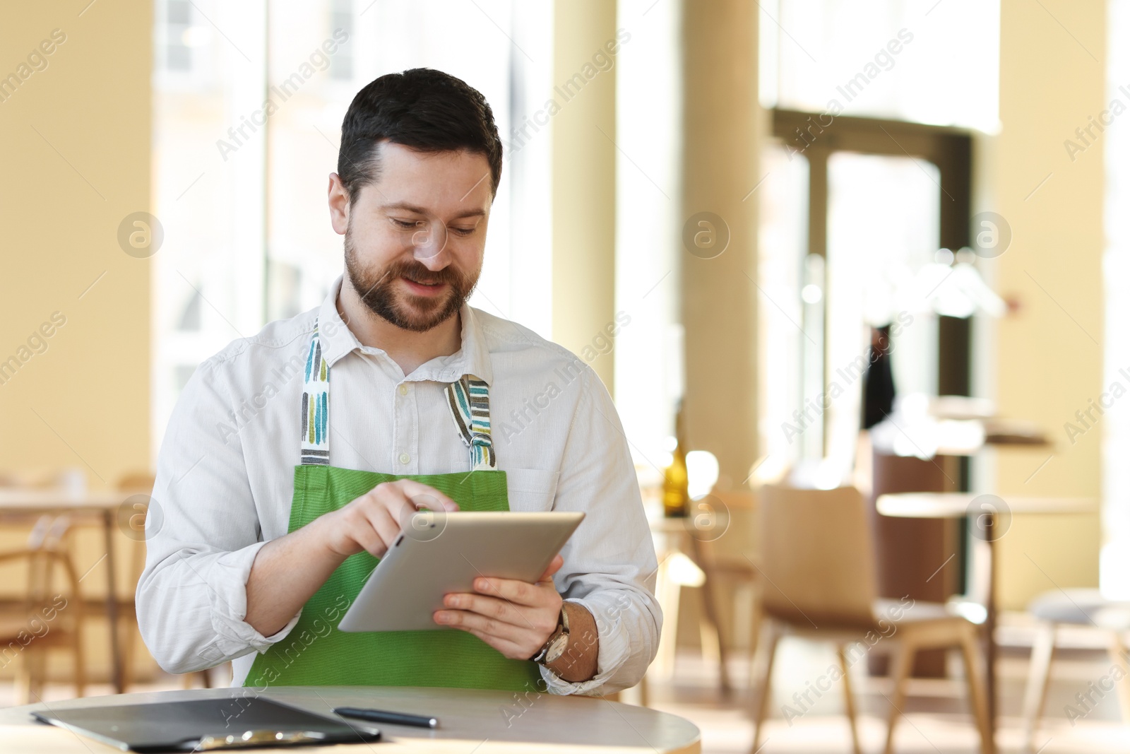 Photo of Handsome business owner working with tablet in his cafe. Space for text