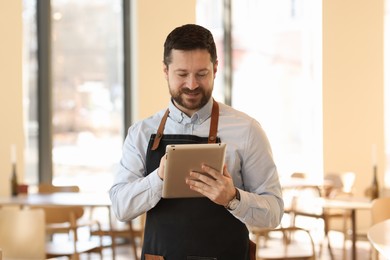 Handsome business owner working with tablet in his cafe