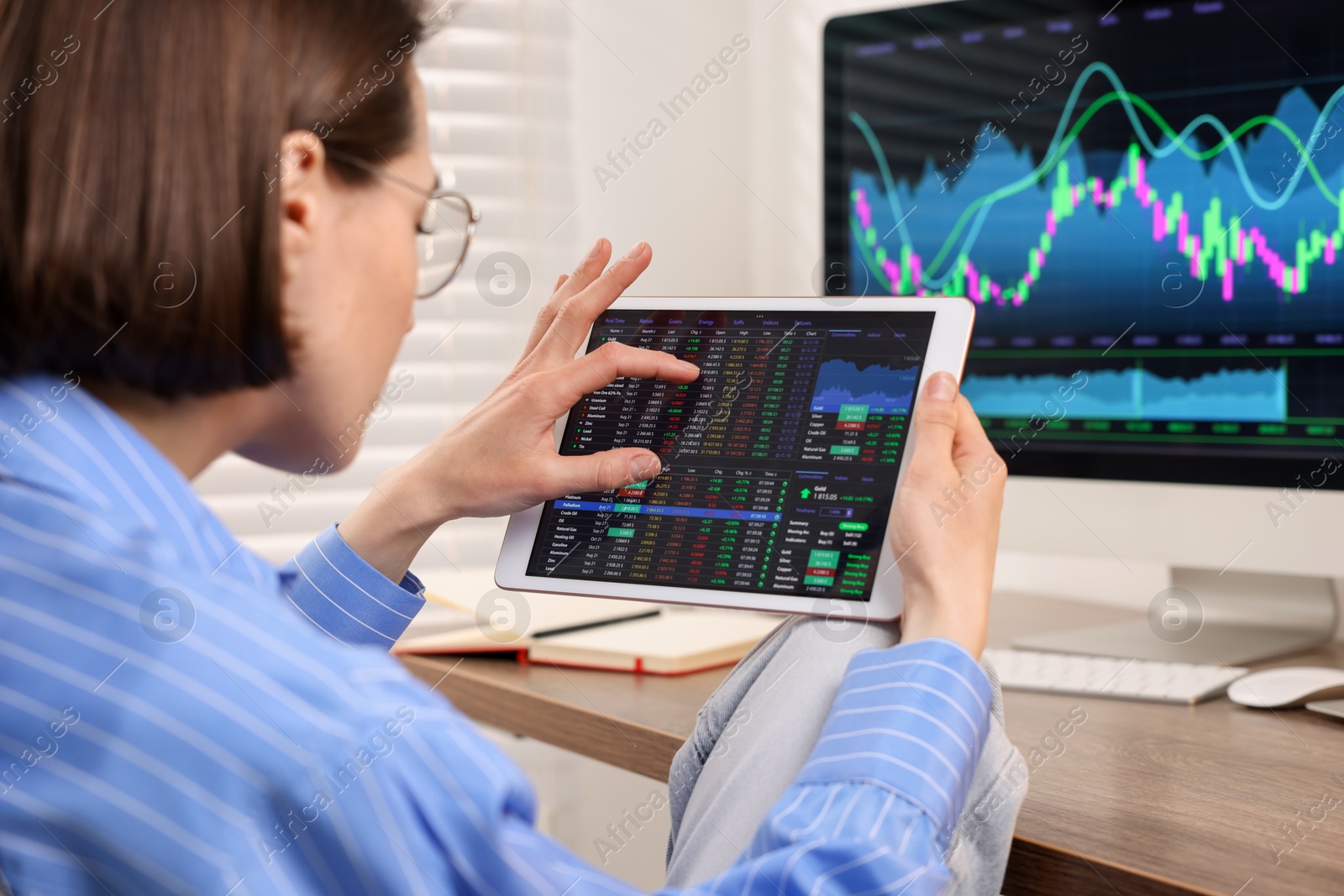 Photo of Stock exchange. Woman analysing financial market on tablet at wooden table indoors