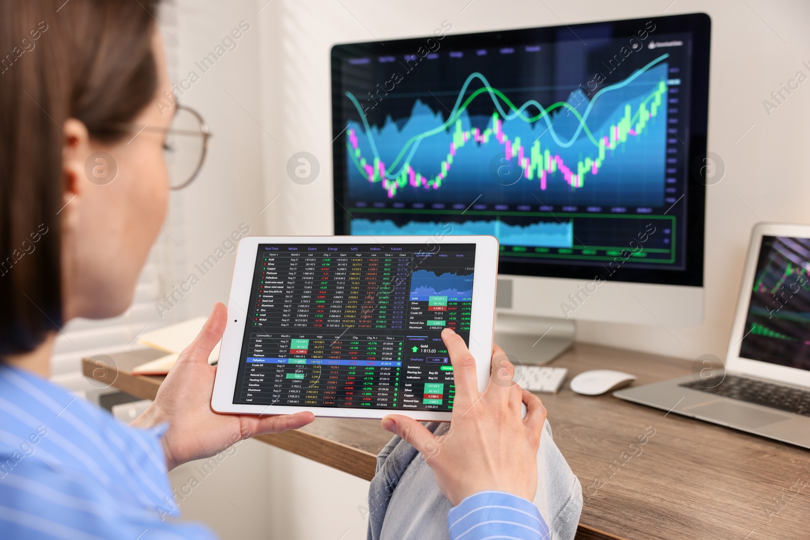 Photo of Stock exchange. Woman analysing financial market on tablet at wooden table indoors