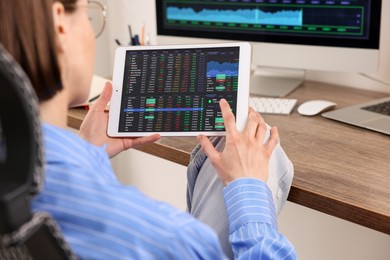 Photo of Stock exchange. Woman analysing financial market on tablet at wooden table indoors