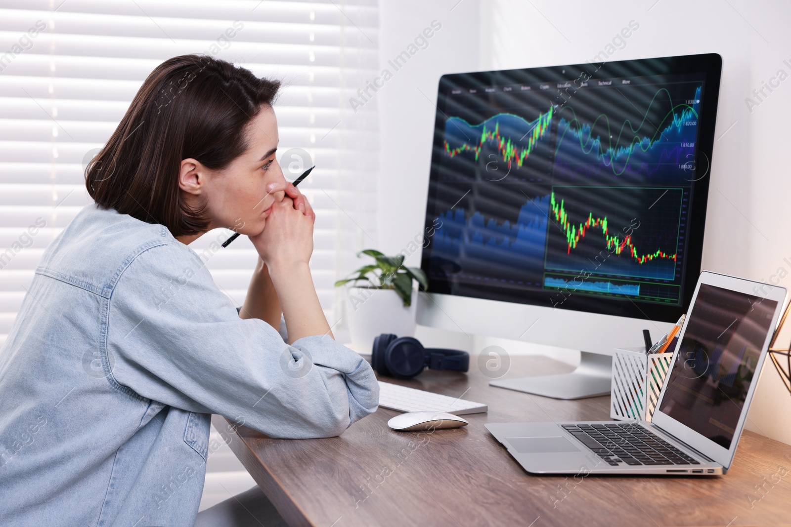 Photo of Stock exchange. Woman analysing financial market on computer at wooden table indoors