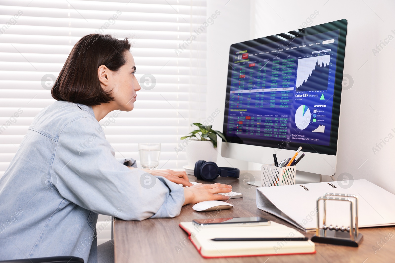 Photo of Stock exchange. Woman analysing financial market on computer at wooden table indoors