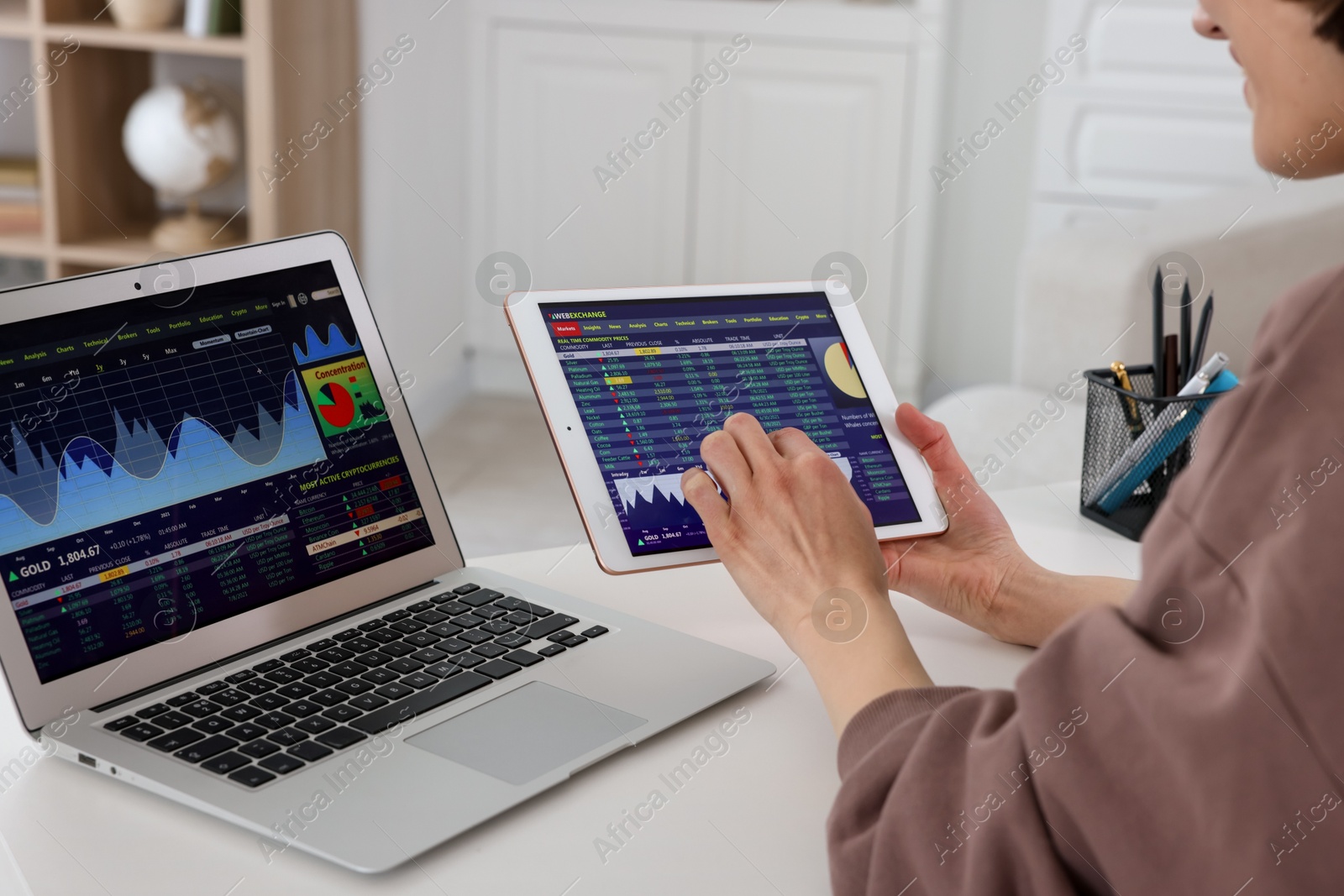 Photo of Stock exchange. Woman analysing financial market on tablet at white table indoors, closeup