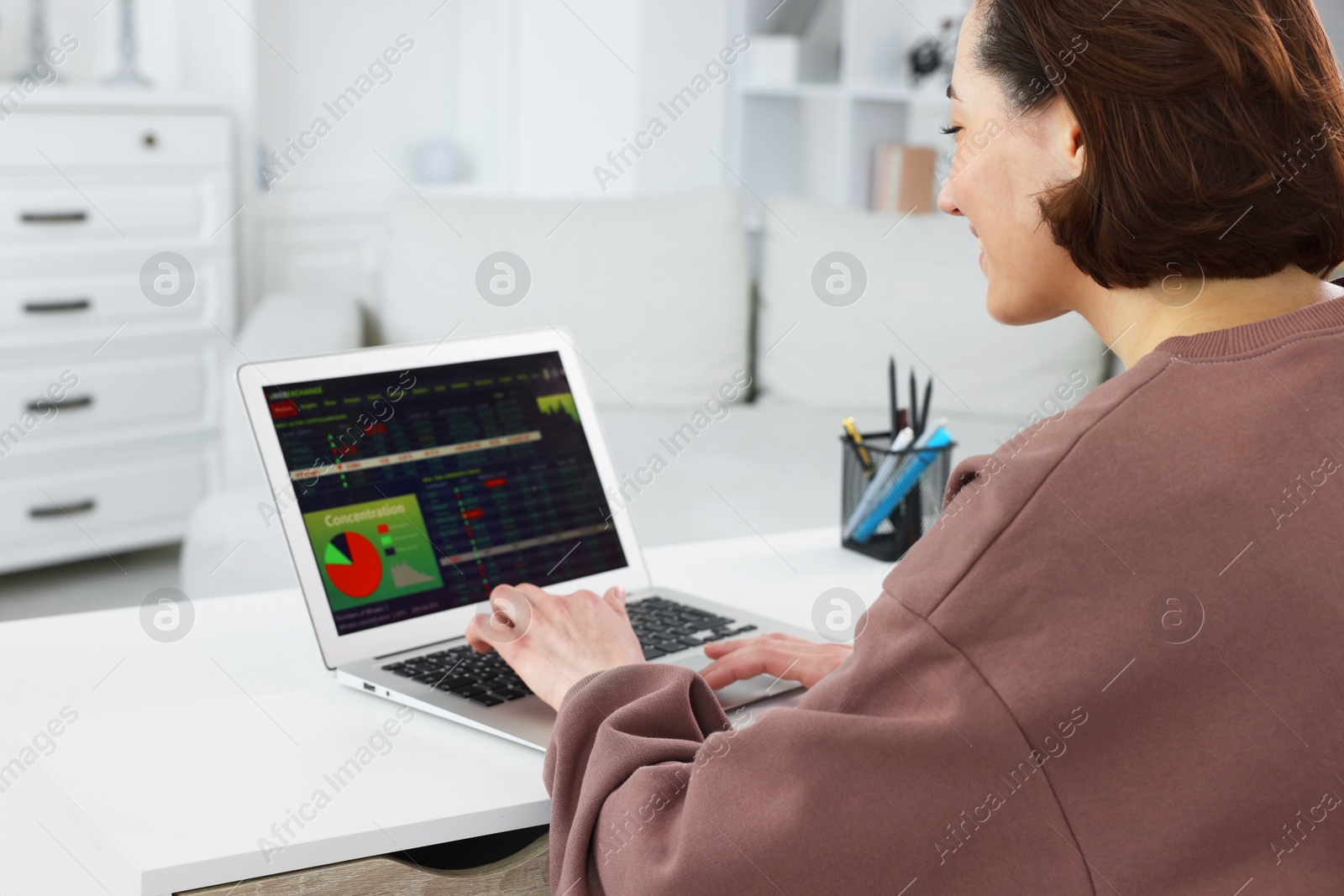 Photo of Stock exchange. Woman analysing financial market on laptop at white table indoors