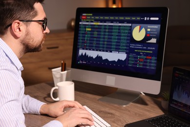 Photo of Stock exchange. Man analysing financial market on computer at desk indoors