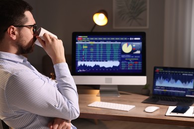 Stock exchange. Man drinking coffee while analysing financial market at desk indoors