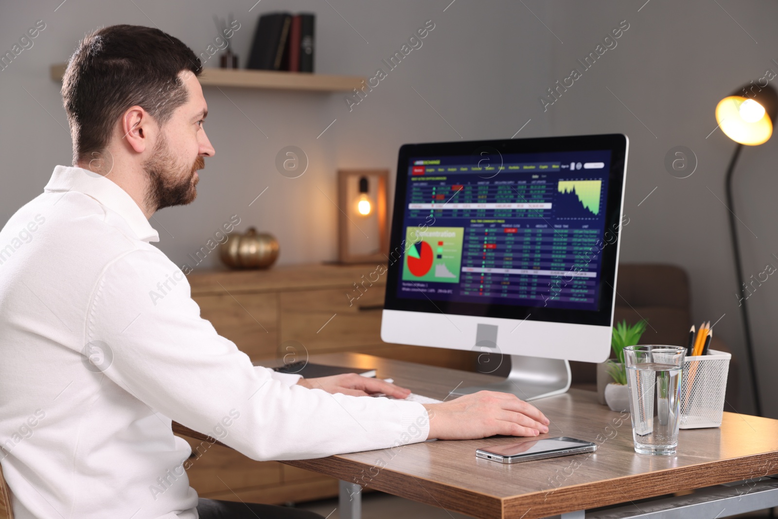 Photo of Stock exchange. Man analysing financial market on computer at desk indoors