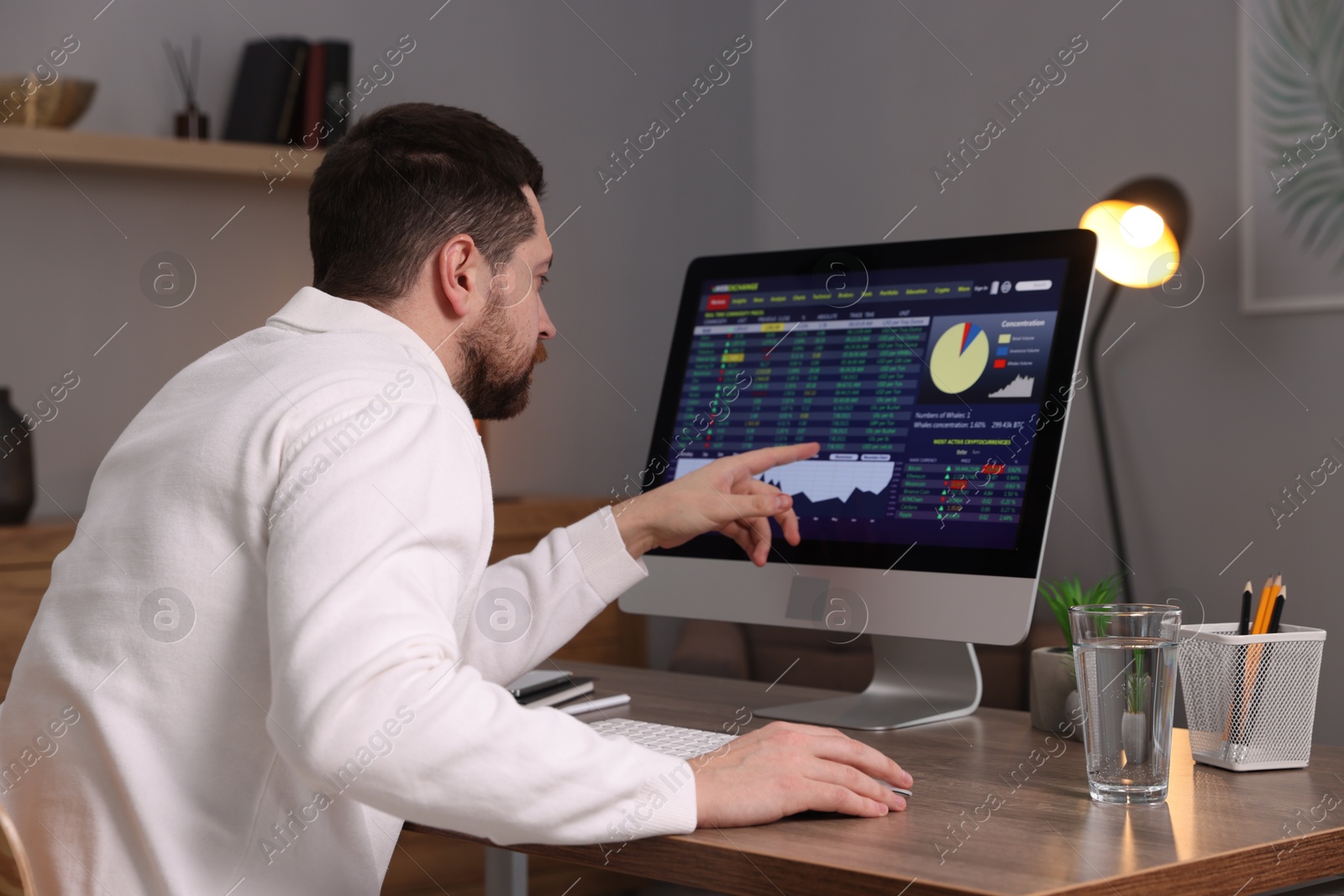 Photo of Stock exchange. Man analysing financial market on computer at desk indoors