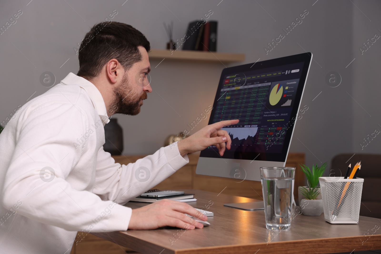 Photo of Stock exchange. Man analysing financial market on computer at desk indoors