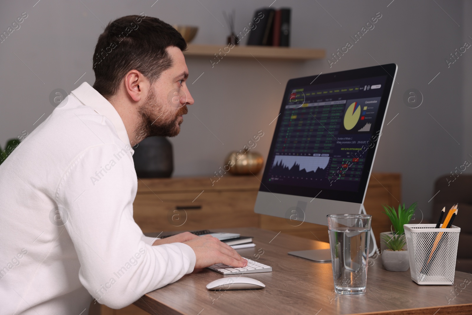 Photo of Stock exchange. Man analysing financial market on computer at desk indoors