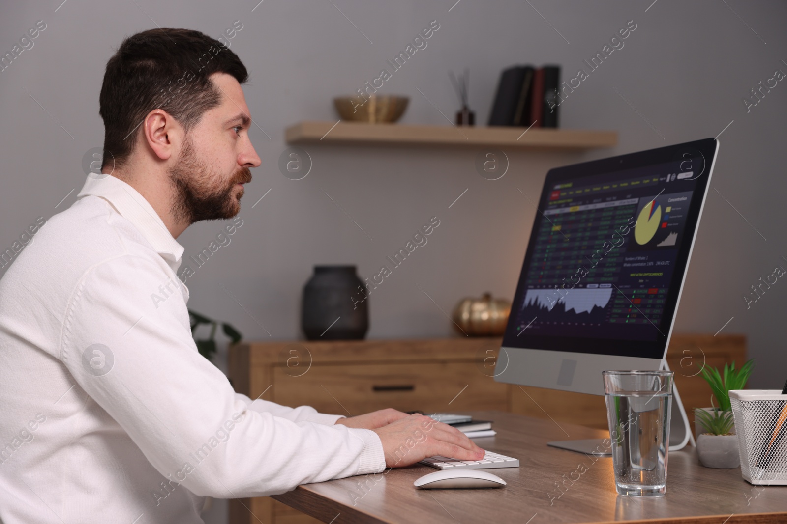 Photo of Stock exchange. Man analysing financial market on computer at desk indoors