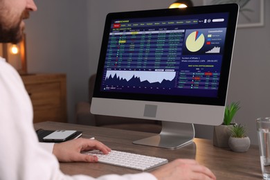 Stock exchange. Man analysing financial market on computer at desk indoors, closeup