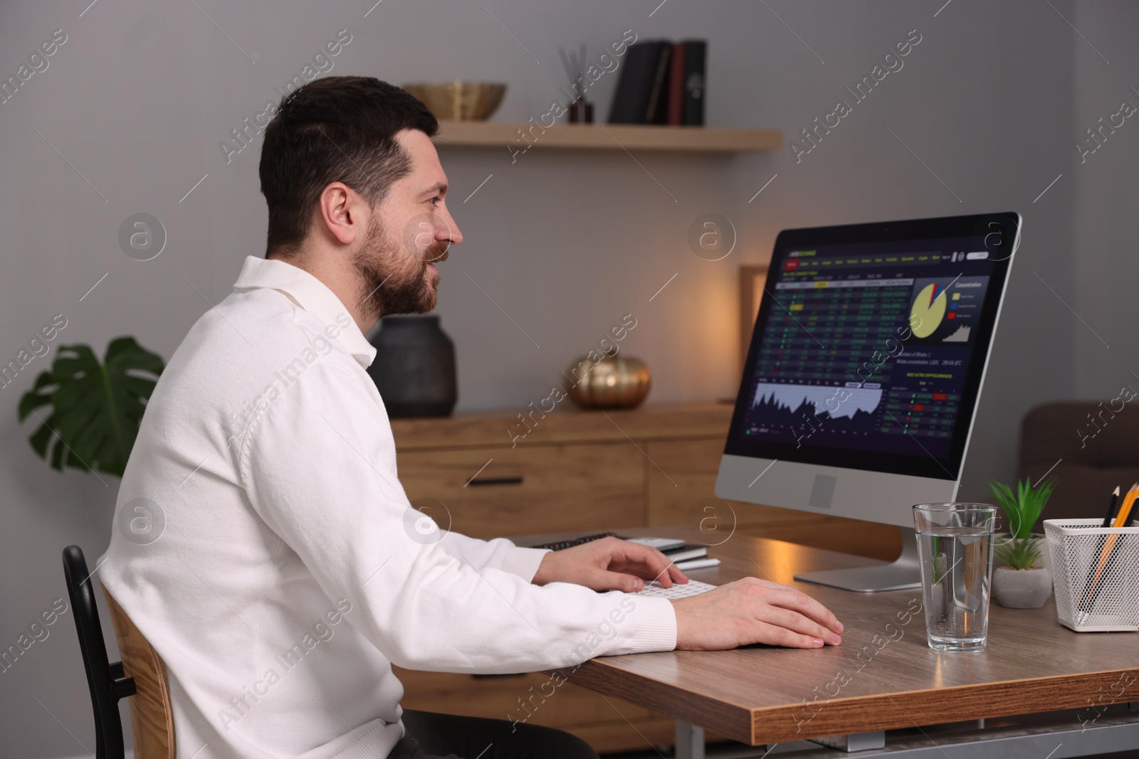 Photo of Stock exchange. Man analysing financial market on computer at desk indoors