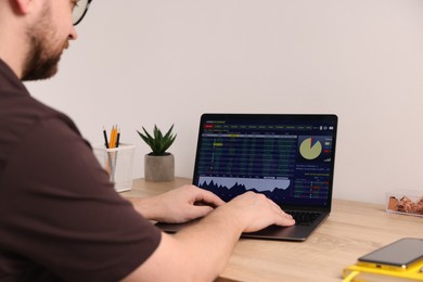 Photo of Stock exchange. Man analysing financial market on laptop at desk indoors, closeup