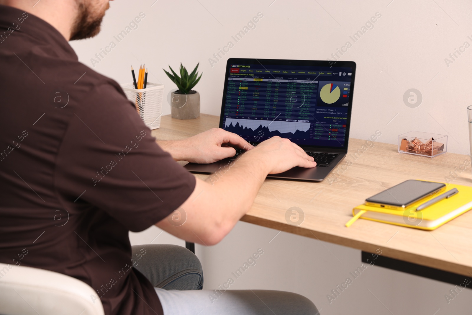 Photo of Stock exchange. Man analysing financial market on laptop at desk indoors, closeup