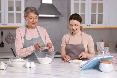 Photo of Happy women cooking by recipe book in kitchen