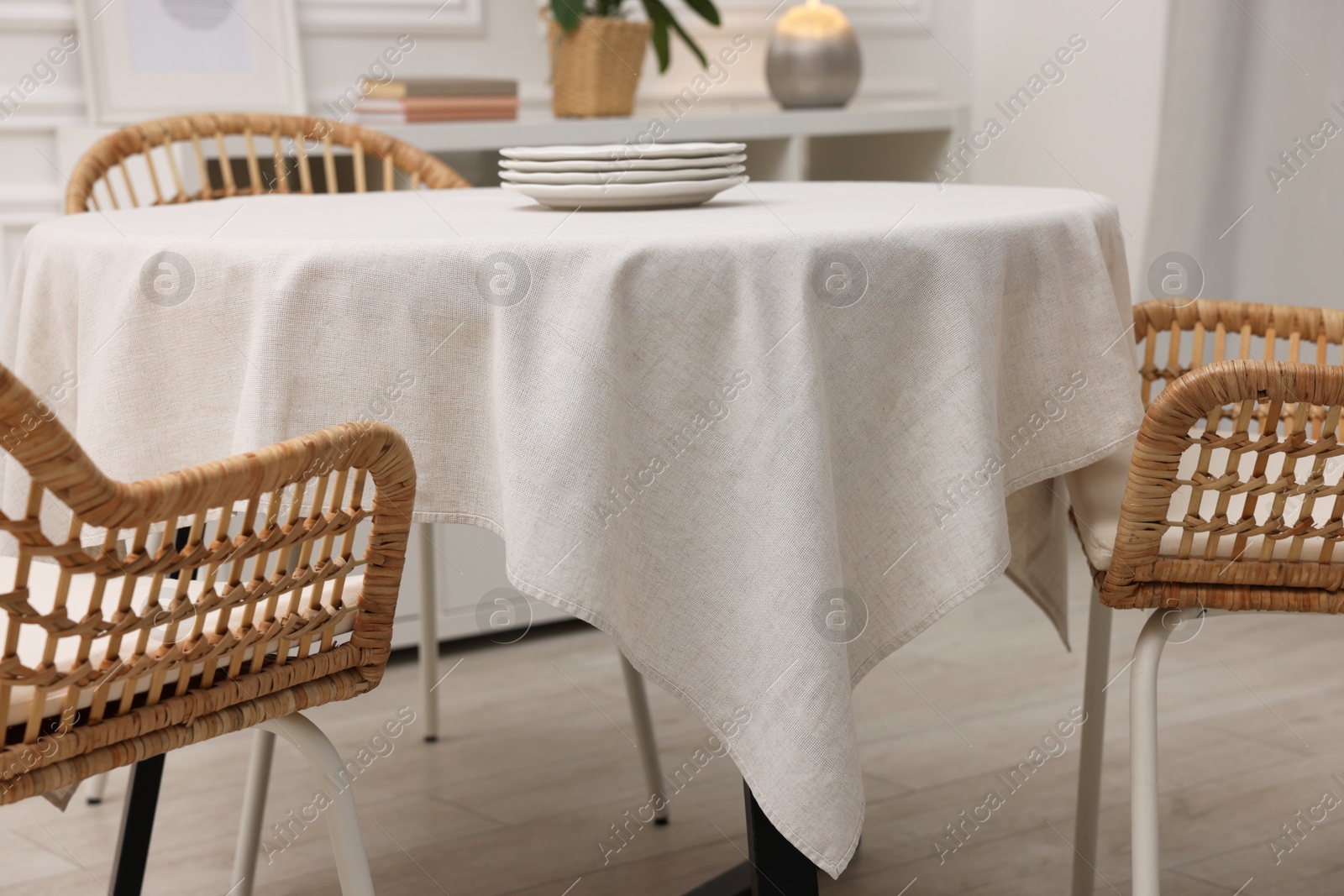 Photo of Table with white tablecloth, plates and chairs in stylish room