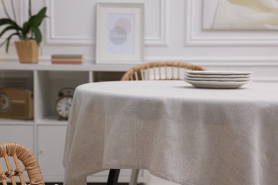 Photo of Table with white tablecloth and plates in room, closeup