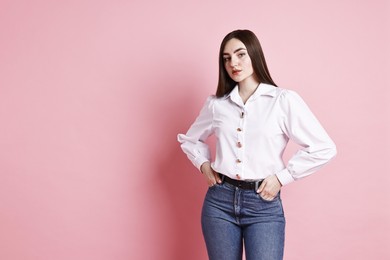 Woman in stylish jeans on pink background. Space for text