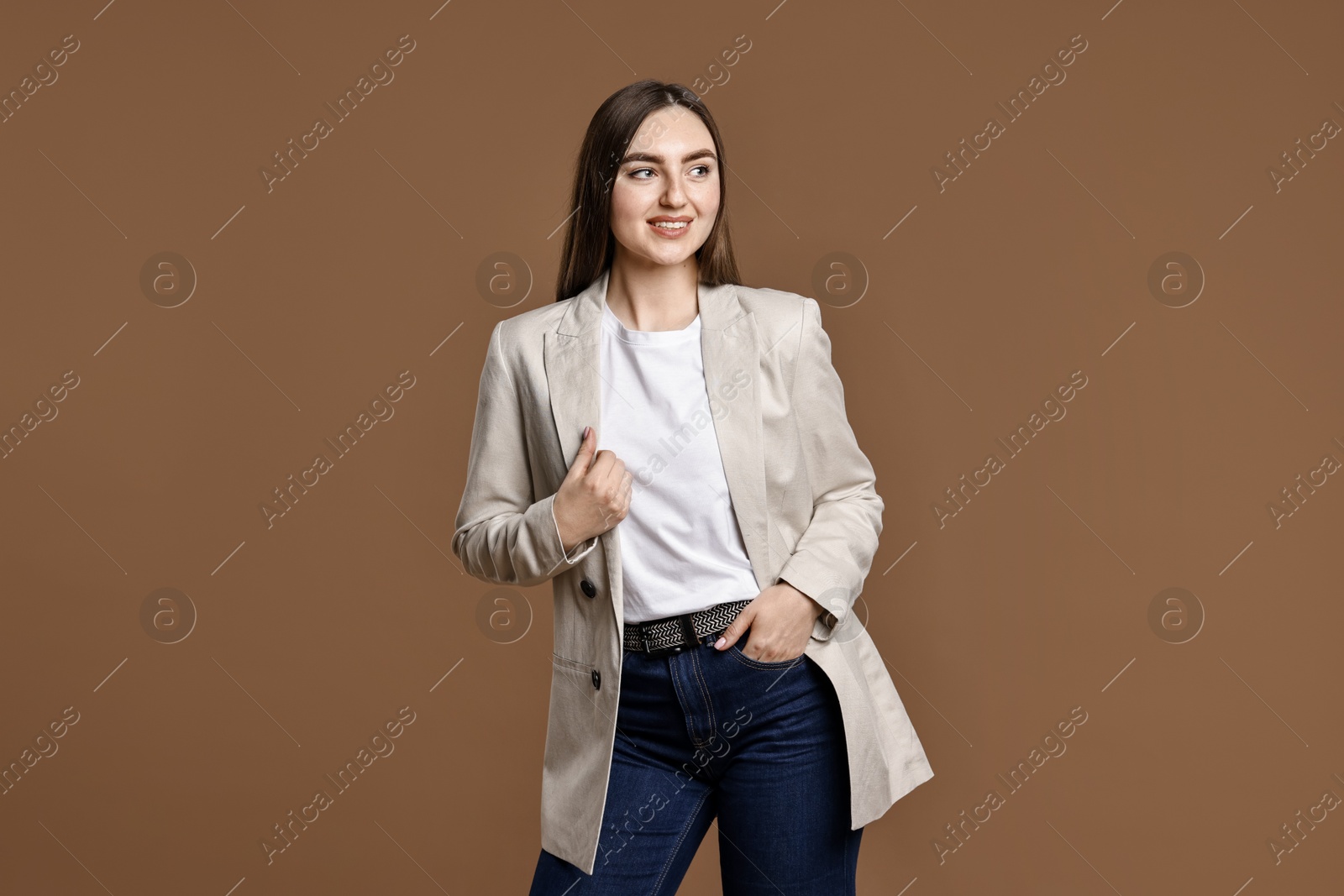 Photo of Smiling woman in stylish jeans on brown background