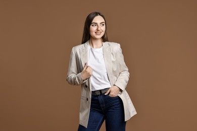 Smiling woman in stylish jeans on brown background