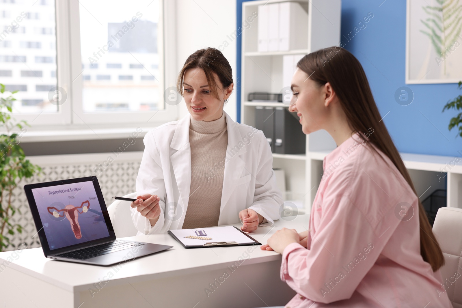 Photo of Contraception. Gynecologist showing image of female reproductive system to woman in clinic