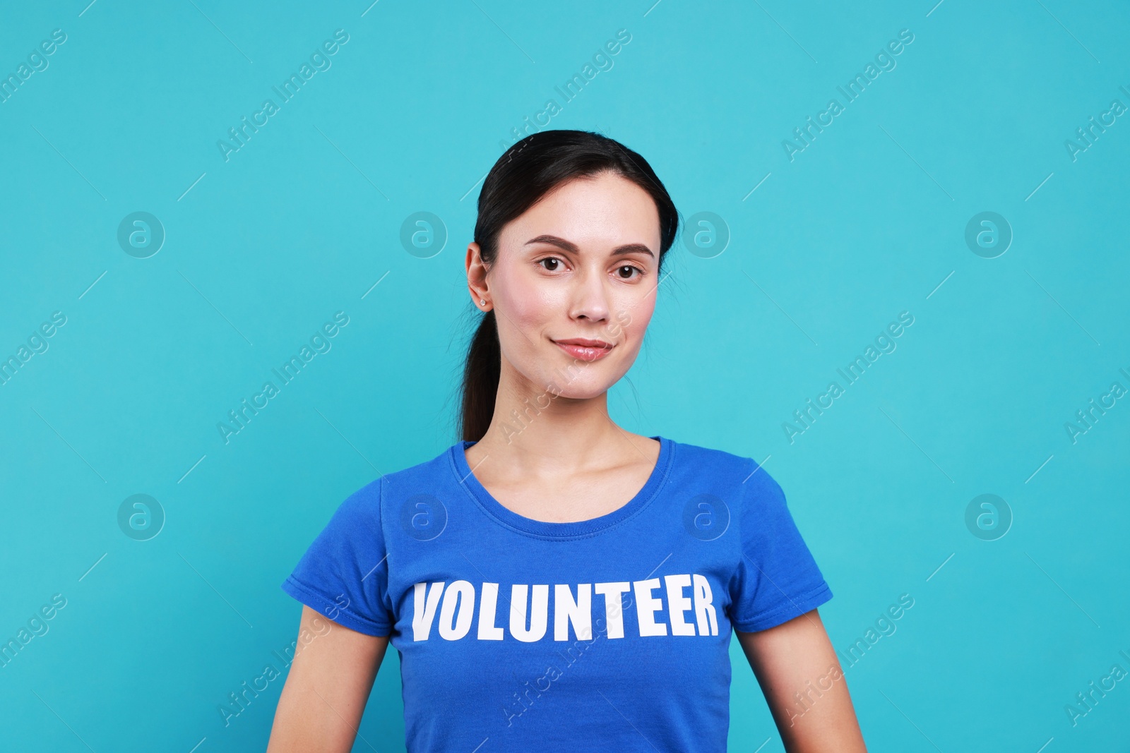 Photo of Young beautiful volunteer wearing t-shirt with printed word on light blue background