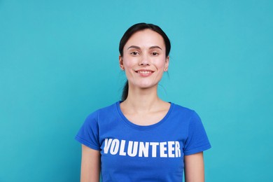 Young beautiful volunteer wearing t-shirt with printed word on light blue background