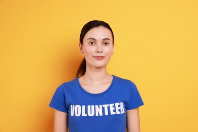 Photo of Young beautiful volunteer wearing t-shirt with printed word on orange background