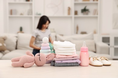 Photo of Baby's stuff on white table and mother packing bag, selective focus