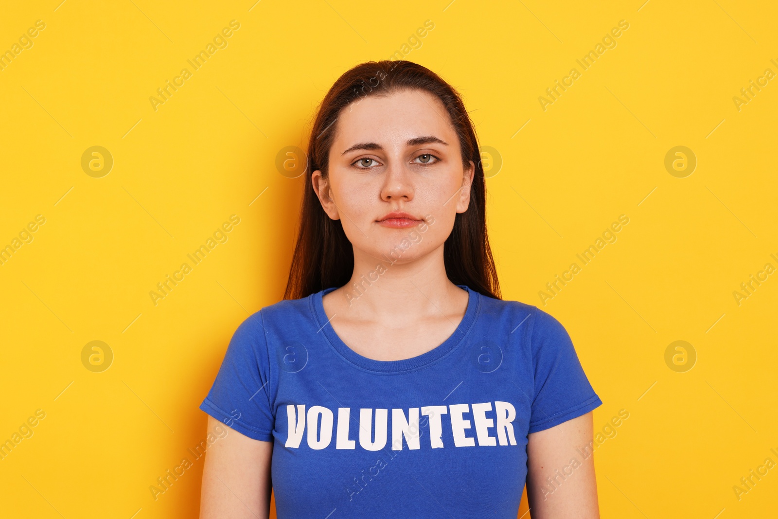 Photo of Portrait of woman in t-shirt with word Volunteer on orange background