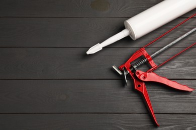 Glue gun and tube on gray wooden background, flat lay. Space for text