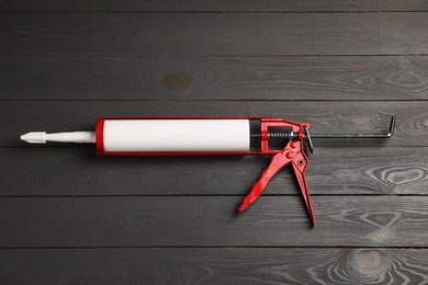 Photo of Glue gun on gray wooden background, top view