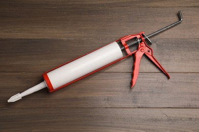 Photo of One glue gun on wooden background, top view. Construction tool