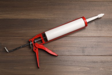 Photo of One glue gun on wooden background, top view. Construction tool