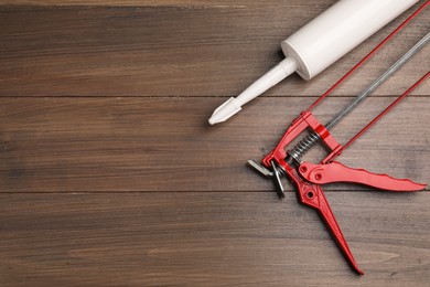 Photo of One glue gun and tube on wooden background, top view with space for text. Construction tool