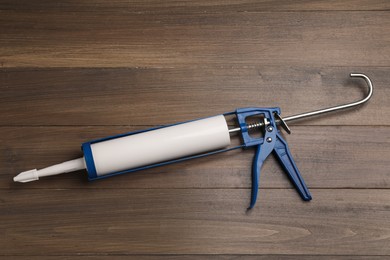 Photo of One glue gun on wooden background, top view. Construction tool