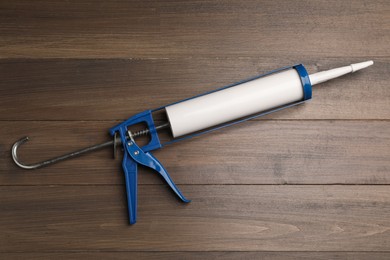 Photo of One glue gun on wooden background, top view. Construction tool