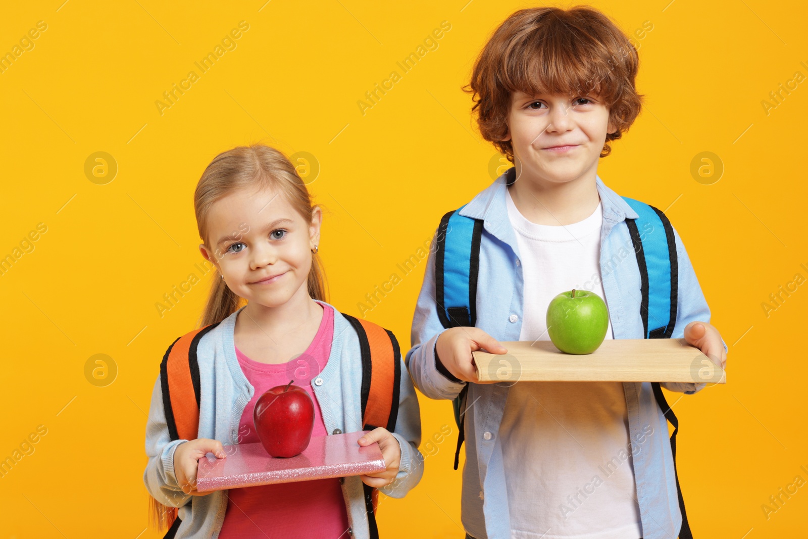 Photo of School children with books and apples on orange background