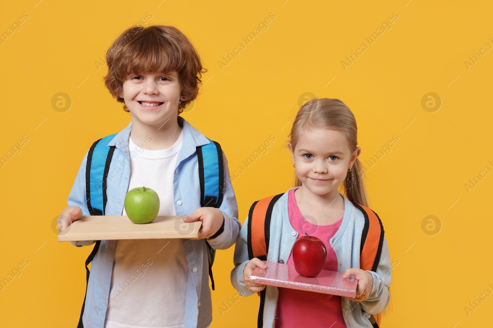 Photo of School children with books and apples on orange background